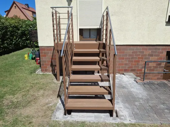Außentreppe aus Stahl mit braunen WPC-Stufen und Edelstahl-Handlauf am Wohnhaus