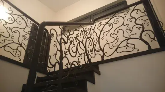 Massive Innentreppe aus Metall mit Ornamentgeländer