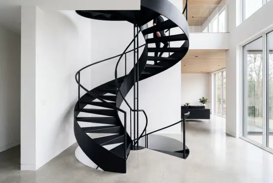Minimalistische Spindeltreppe aus mattschwarzem Stahl in modernem weißen Innenraum