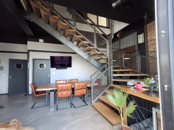 Halbgewendelte Stahltreppe mit Massivholzstufen in einem Gastraum im Industriestil