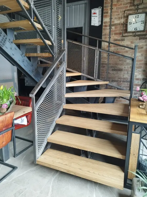 Detail einer Stahltreppe mit Massivholzstufen und Geländer mit Streckgitterfüllung