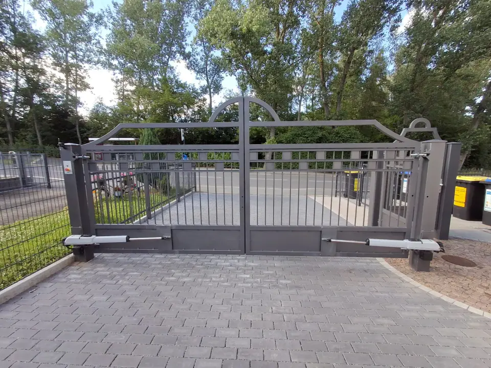 Breites anthrazitfarbenes Schiebetor aus Stahl an einer gepflasterten Hofeinfahrt