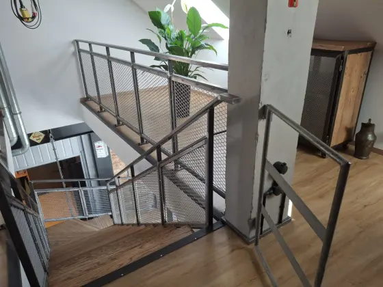 Graues Stahlgeländer mit Gitterfüllung in einem Treppenhaus